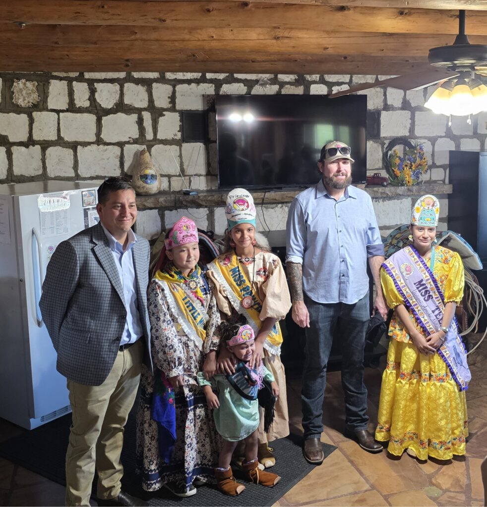 Assistant Secretary Billy Kirkland, Congressman Eli Crane, and four Yavapai-Apache Nation Royalty stand together inside a stone-walled room at Cloverleaf Ranch following the reception.