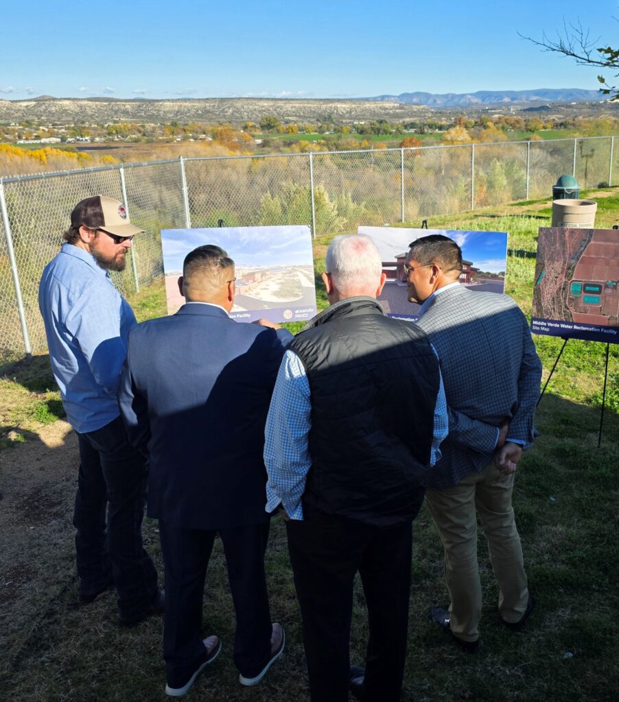 Congressman Crane, Chairman Rocha, Attorney General Scott Canty, and Assistant Secretary Kirkland stand at the Tunlii Community Park overlook reviewing display boards, with the Verde River and the Middle Verde wastewater facility site visible in the background.